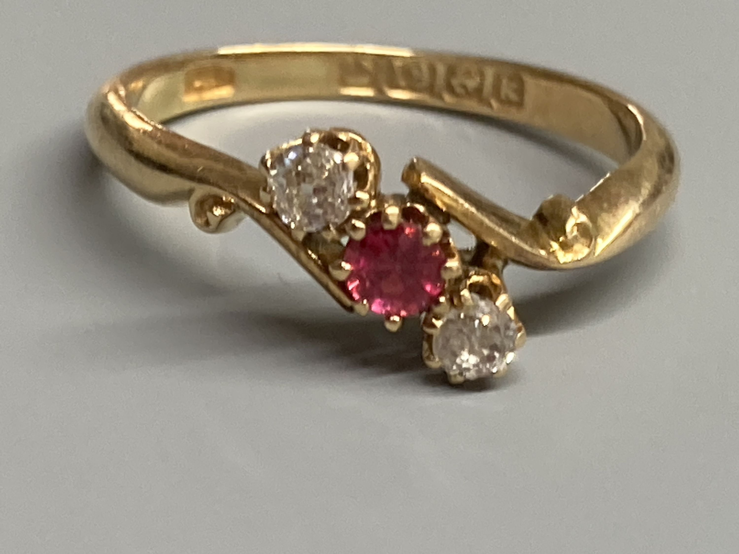 An Edwardian 18ct gold, red spinel and diamond set three stone crossover ring, size O, gross 2.9 grams